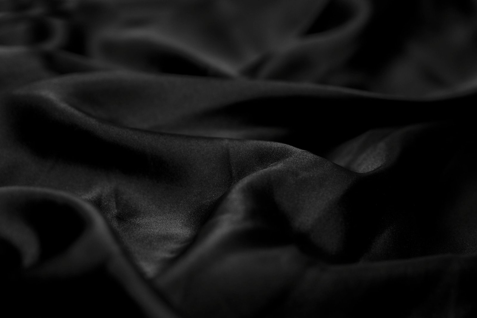 Luxurious black satin fabric with gentle waves and soft texture, perfect for backgrounds.